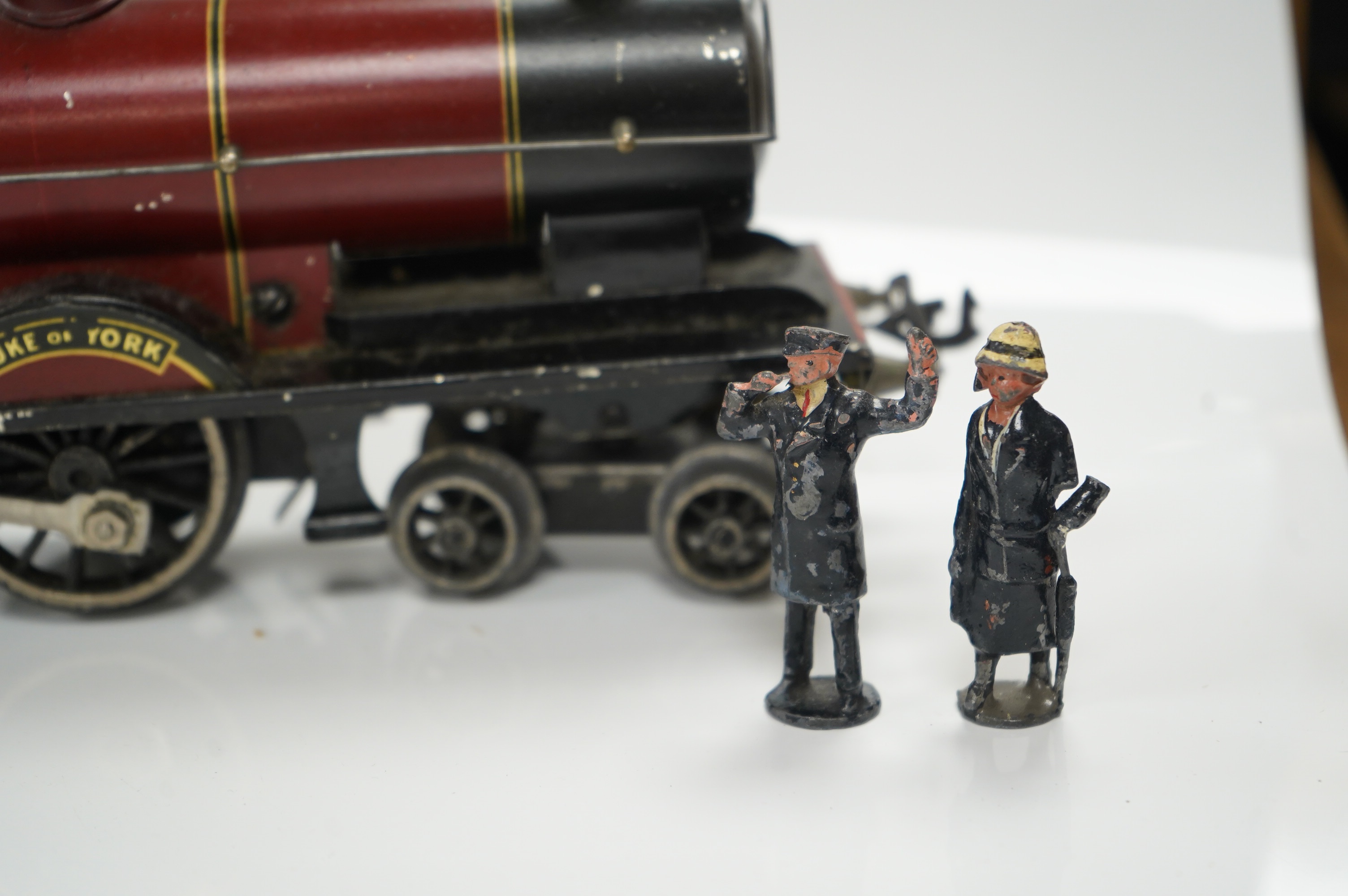 A Bassett Lowke O gauge tinplate clockwork 4-4-0 tender locomotive (missing tender), Duke of York, together with four Crescent/Britains lead railway figures and a milk churn. Condition poor to fair.